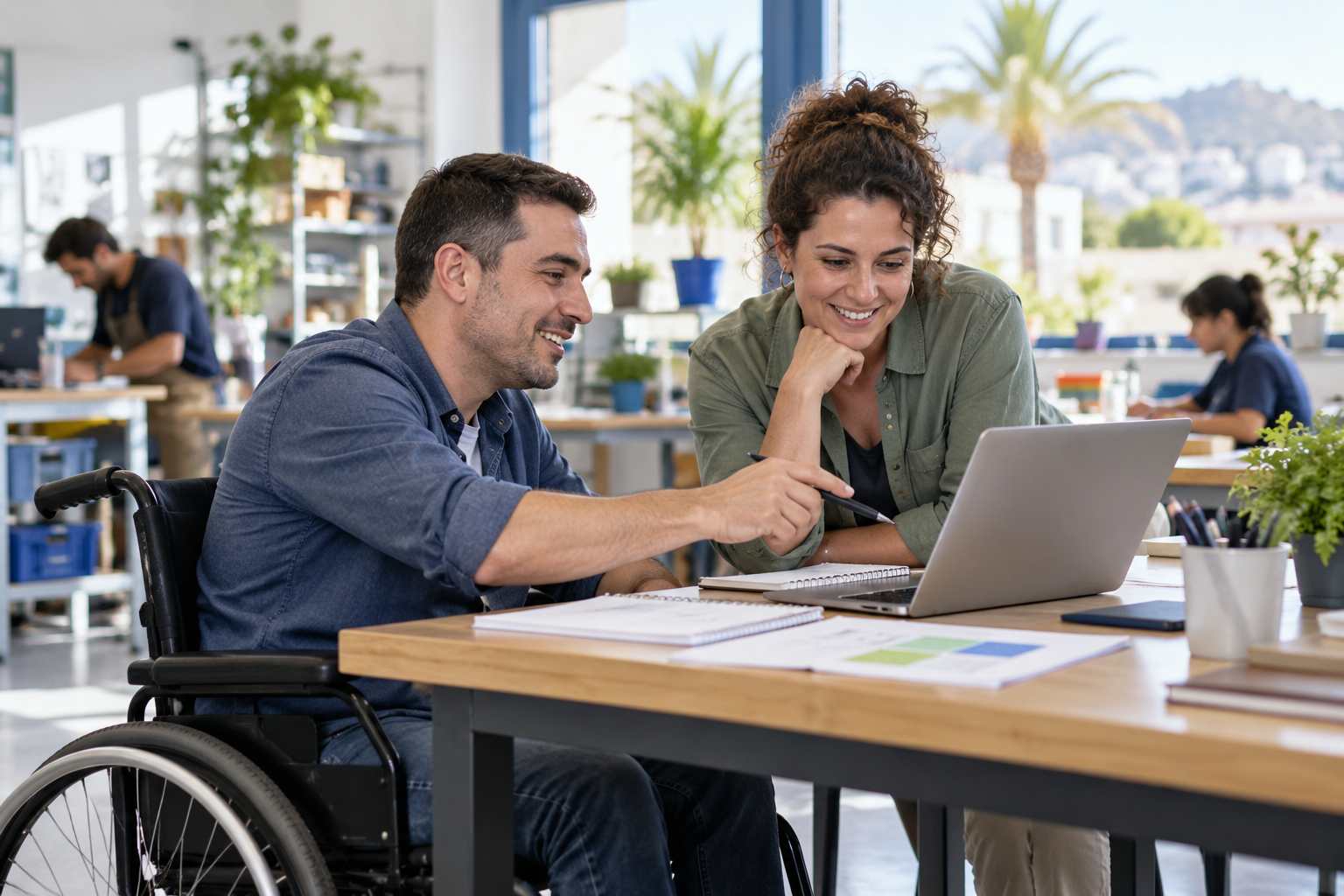Dos personas colaboran en una actividad de formación digital; una de ellas utiliza una silla de ruedas